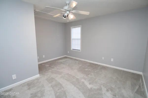 an empty room with windows and fan