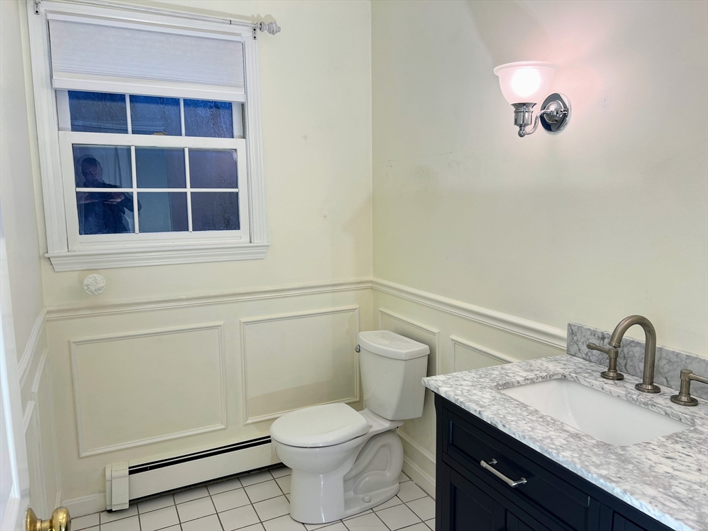 1565 West Street Wrentham, MA 02093 - Photo 13 of 41 a bathroom with a granite countertop sink a toilet and a window
