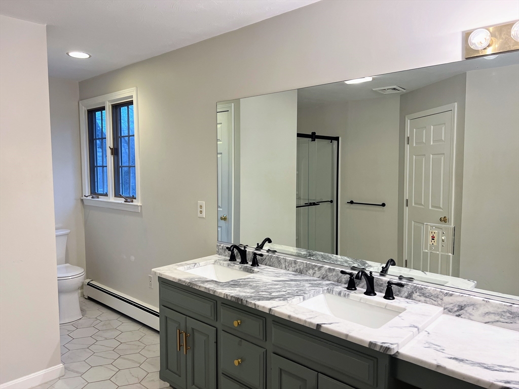 1565 West Street Wrentham, MA 02093 - Photo 8 of 41 a bathroom with a granite countertop sink a toilet and a mirror