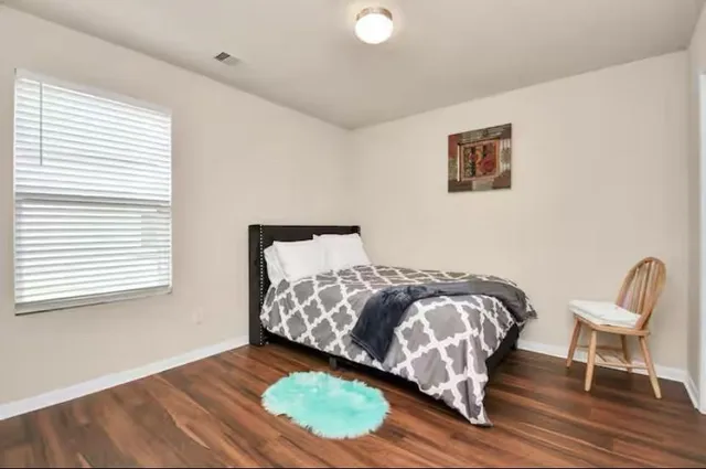 a bed sitting in a bedroom next to a window and a chair