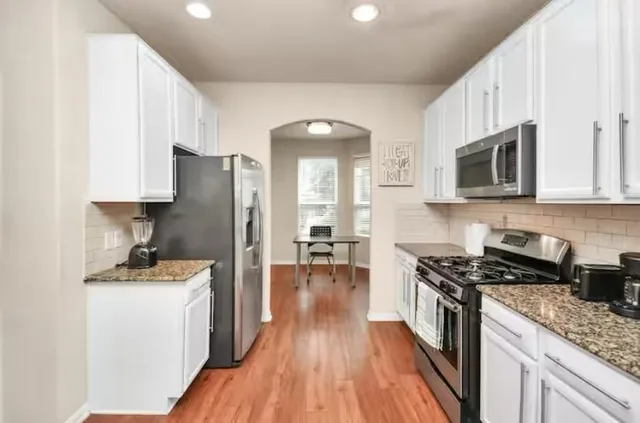 a kitchen with granite countertop a refrigerator stove top oven and sink