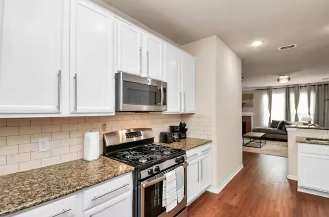 a kitchen with stainless steel appliances granite countertop a stove a sink and a microwave
