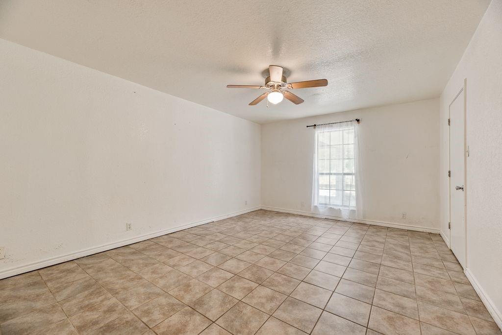 298 Butterfield Road Denison, TX 75021 - Photo 17 of 34 Spacious room featuring neutral-toned tile flooring, a window with natural light, and a ceiling fan with integrated lighting