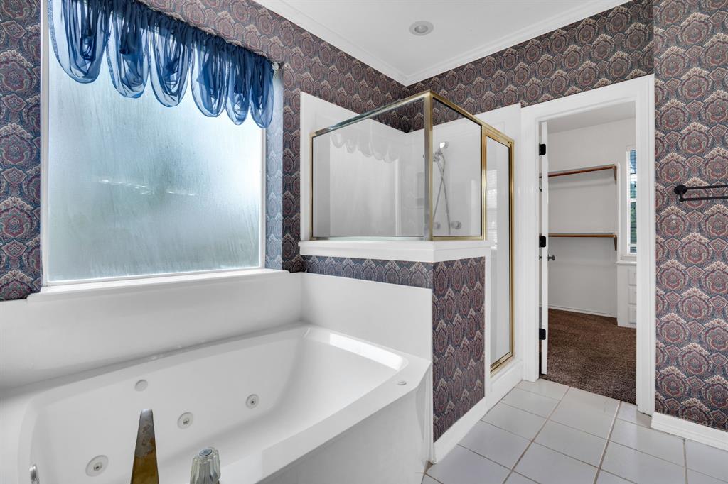 1907 Timber Ridge Court Cedar Hill, TX 75104 - Photo 16 of 30 Bathroom featuring a built-in jetted tub, a frosted window, a glass-enclosed shower with gold-tone framing, patterned wallpaper, and tile flooring