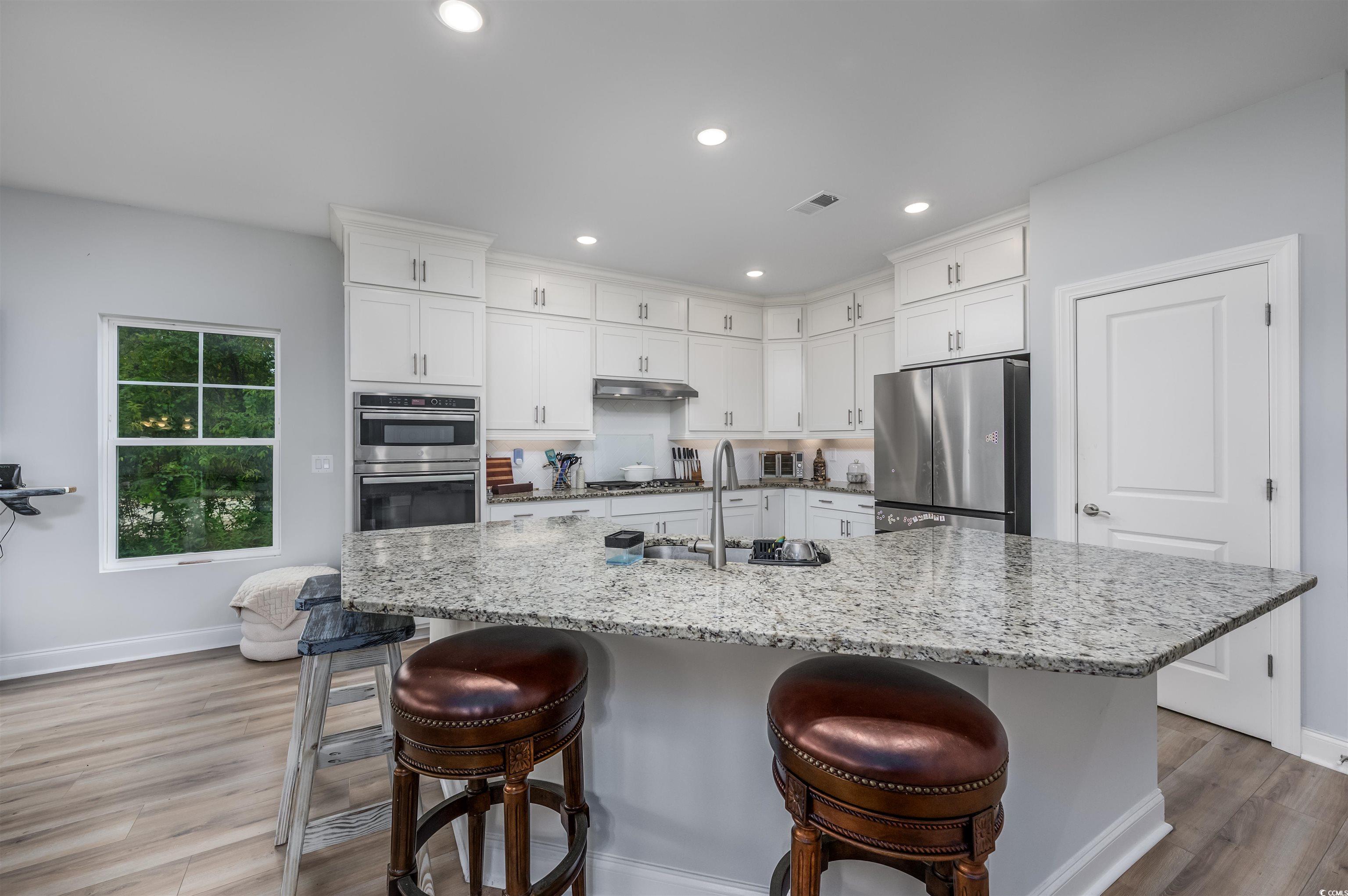2550 Dogwood Road Longs, SC 29568 - Photo 5 of 35 Kitchen with light stone counters, a breakfast bar area, white cabinets, light wood finished floors, and recessed lighting