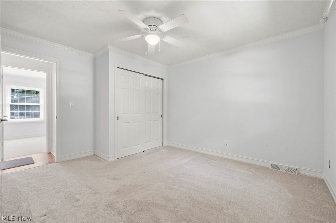 3871 Greentree Road Stow, OH 44224 - Photo 28 of 50 Carpeted room featuring a ceiling fan with integrated lighting, bi-fold closet doors, crown molding, and baseboard trim