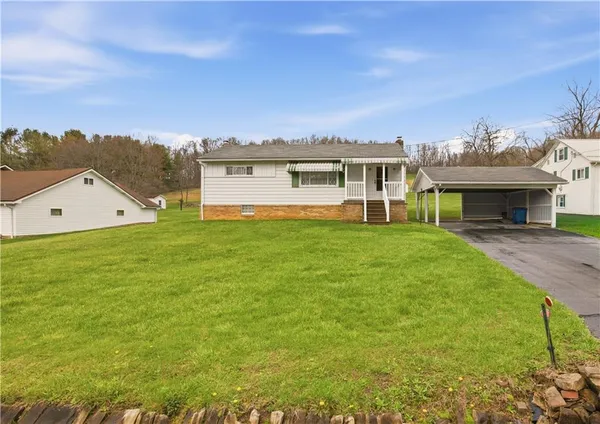 a view of a house with a big yard and large trees