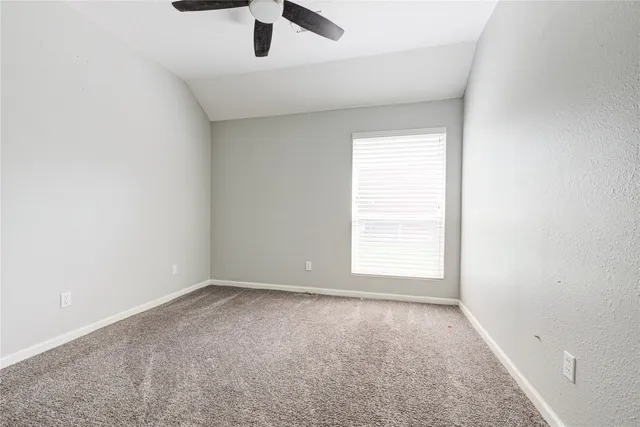 an empty room with a window and a ceiling fan