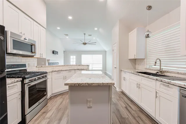 a large kitchen with granite countertop a stove top oven a sink a counter space and cabinets