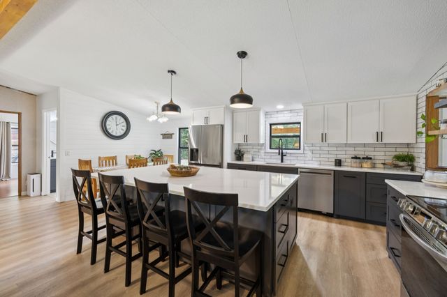 a kitchen with stainless steel appliances a table chairs and a refrigerator