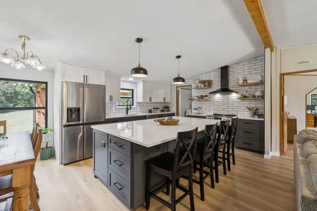 a kitchen with kitchen island granite countertop a sink a counter top space and stainless steel appliances