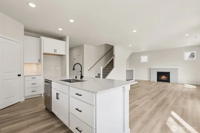 a large kitchen with stainless steel appliances a large counter top a stove a refrigerator and white cabinets