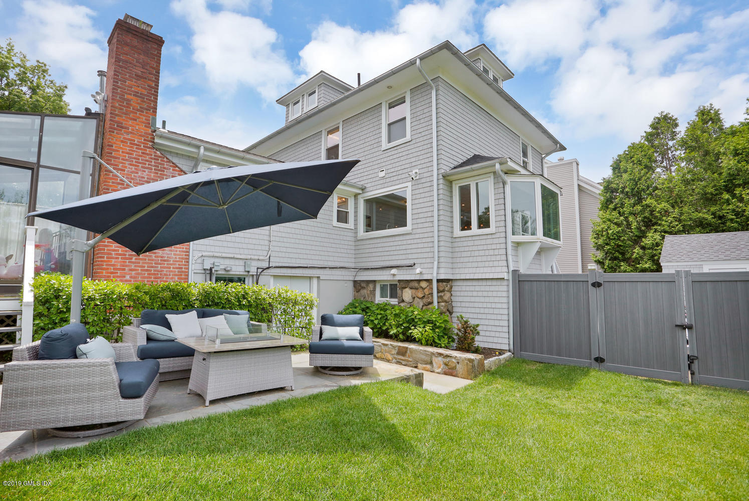 52 Arcadia Road Old Greenwich, CT 06870 - Photo 23 of 28 a patio with a table and chairs under an umbrella