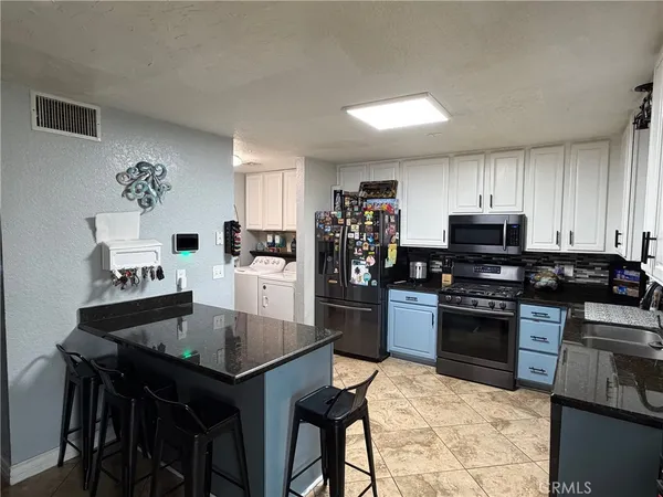 a kitchen with granite countertop stainless steel appliances cabinets a sink and a stove
