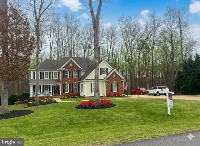 a front view of a house with a garden and trees