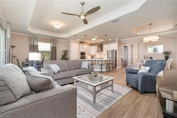 a living room with furniture kitchen view and a chandelier