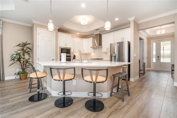 a kitchen with stainless steel appliances kitchen island granite countertop a table chairs refrigerator and sink