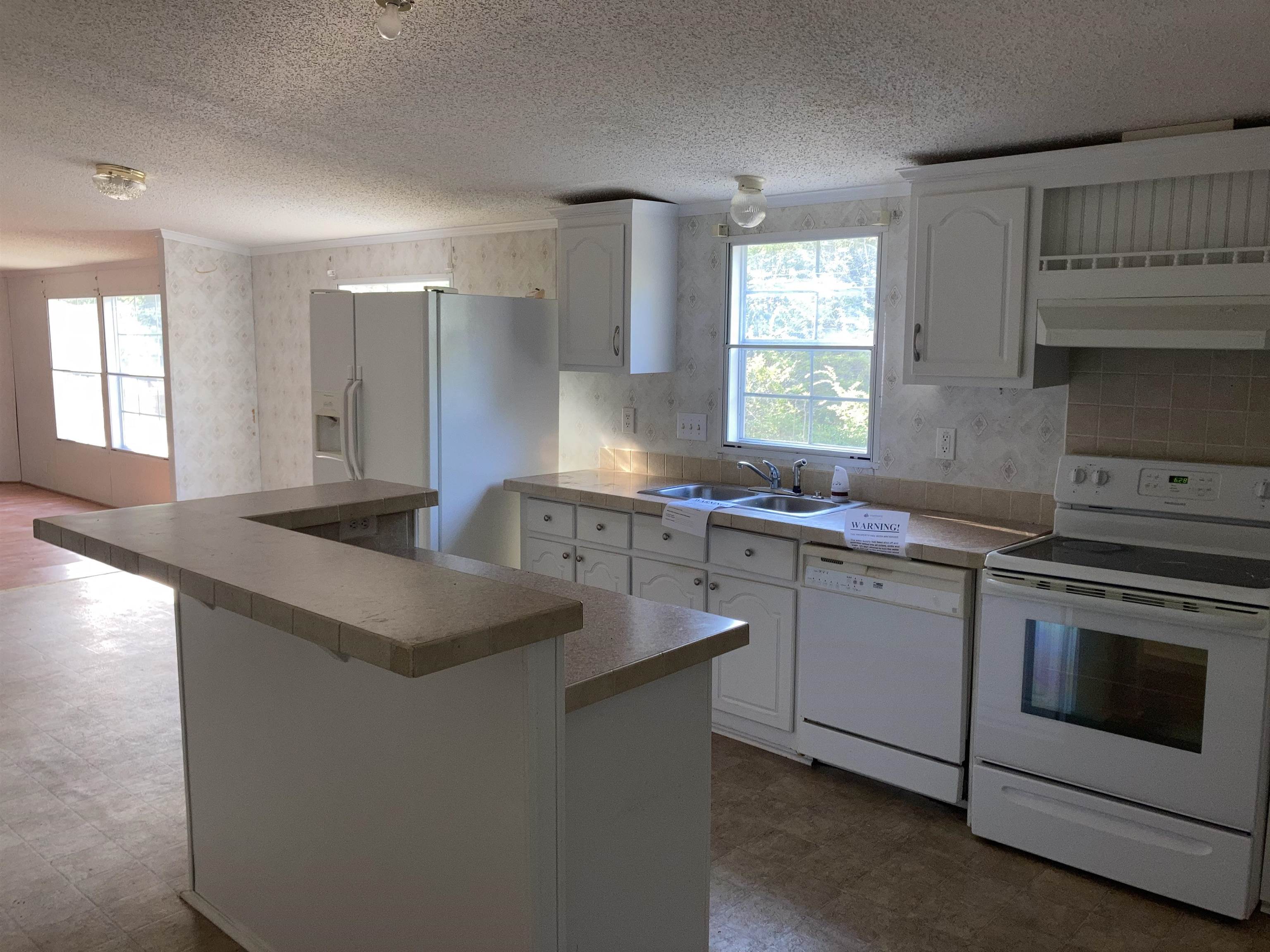 840 Rose Road Somerville, TN 38068 - Photo 13 of 21 Kitchen featuring white appliances, white cabinetry, wallpapered walls, a kitchen breakfast bar, and a textured ceiling