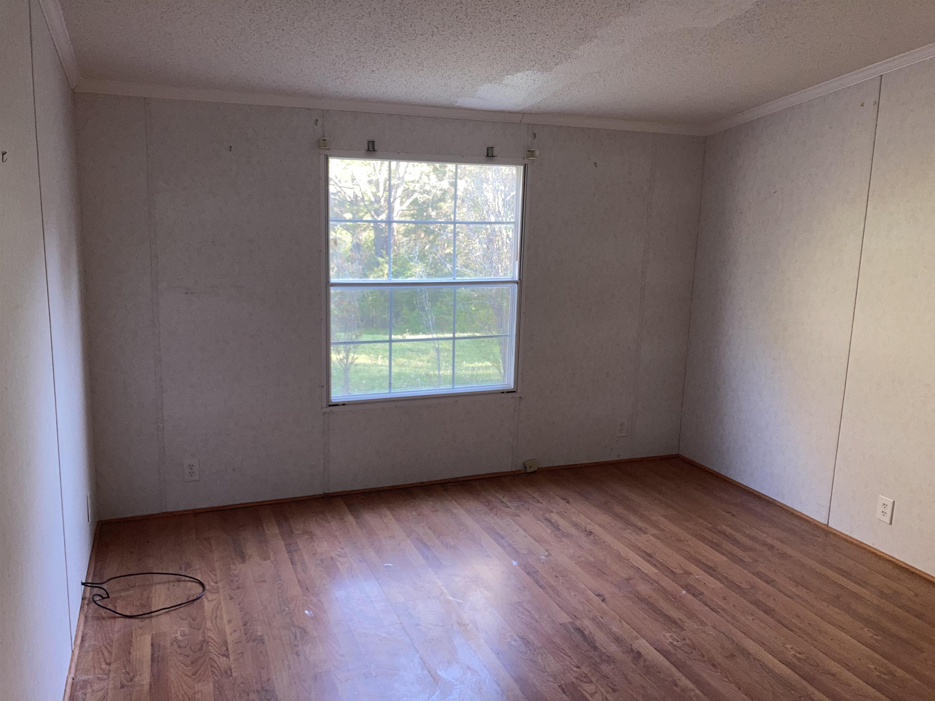 840 Rose Road Somerville, TN 38068 - Photo 16 of 21 Spare room featuring light wood-type flooring, ornamental molding, and a textured ceiling