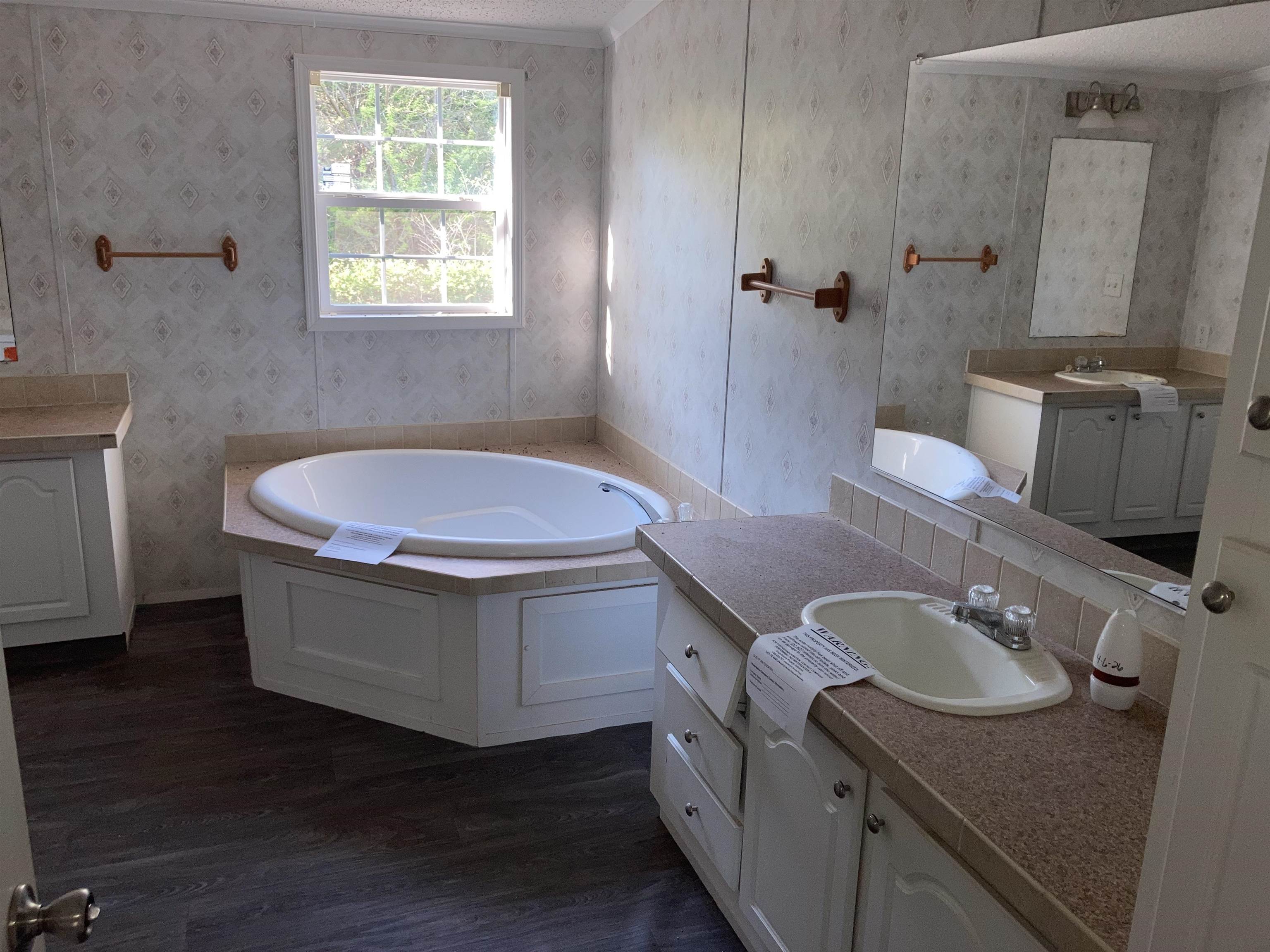 840 Rose Road Somerville, TN 38068 - Photo 5 of 21 Bathroom with two vanities, a garden tub, wallpapered walls, and dark wood-style flooring