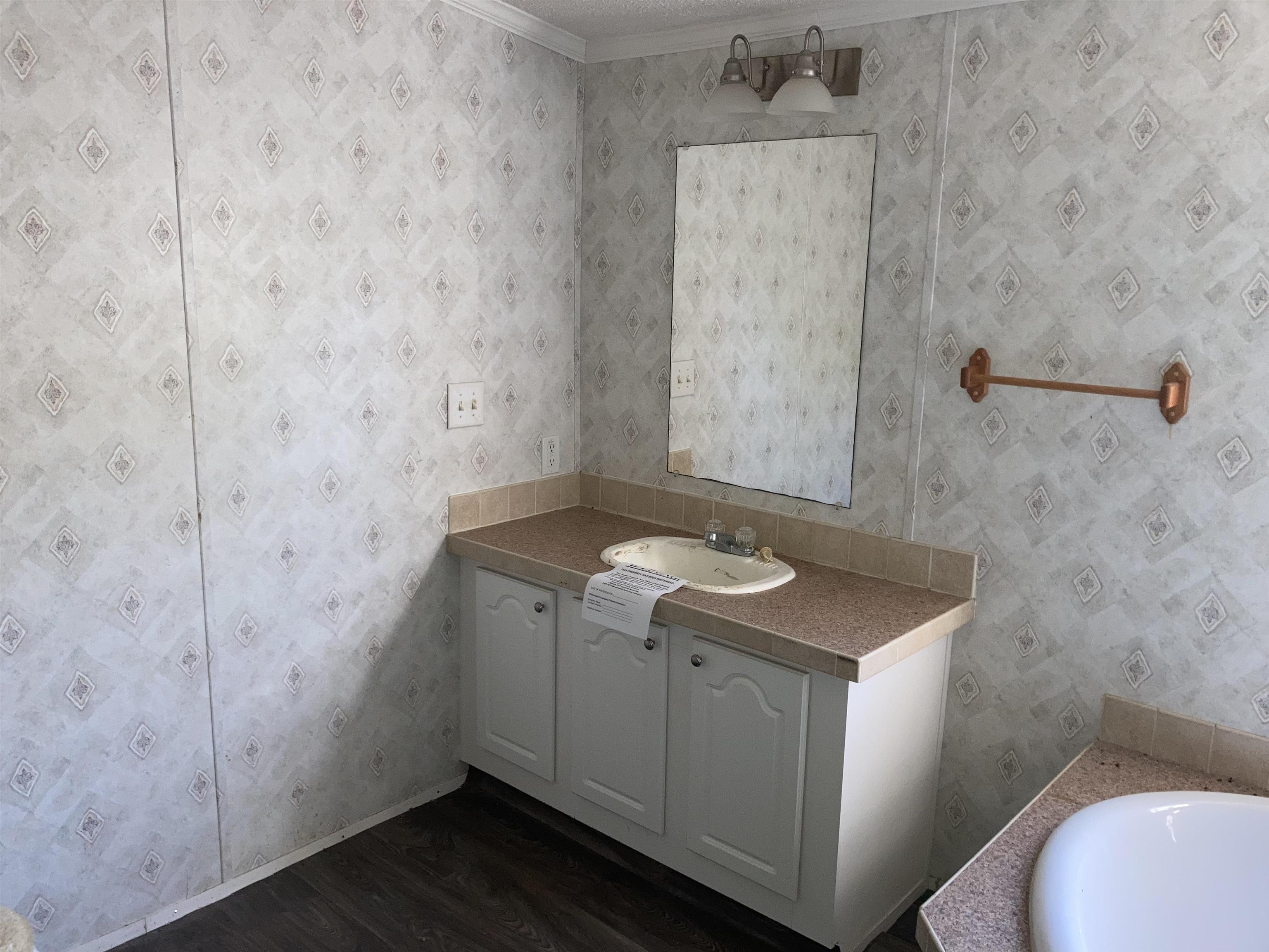 840 Rose Road Somerville, TN 38068 - Photo 6 of 21 Bathroom with vanity, dark wood-style flooring, crown molding, and wallpapered walls