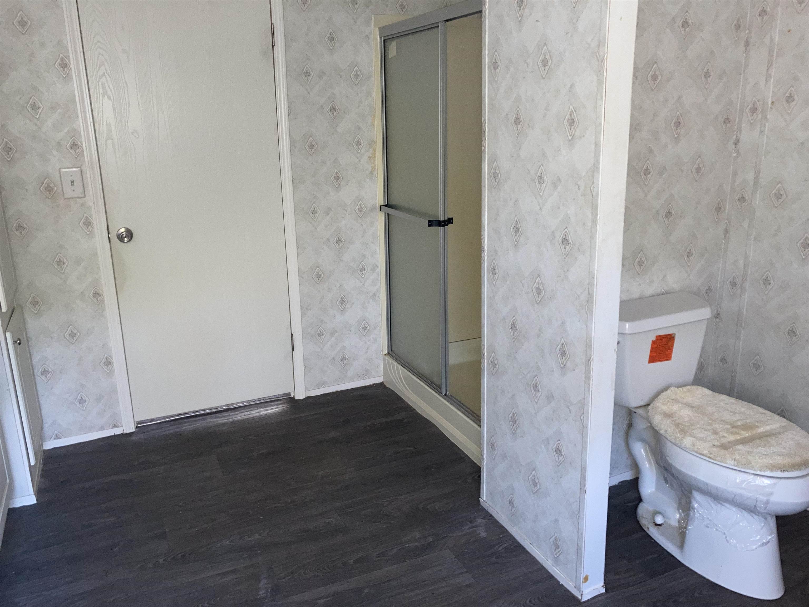 840 Rose Road Somerville, TN 38068 - Photo 7 of 21 Bathroom featuring a shower stall, dark wood-style flooring, and wallpapered walls