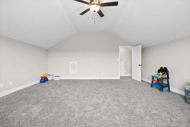 a view of empty room with stairs and a ceiling fan