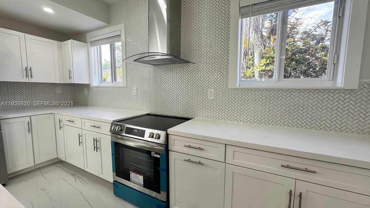 1824 Southwest 24th Street Miami, FL 33145 - Photo 11 of 35 a view of a kitchen with white cabinets and a wooden floor