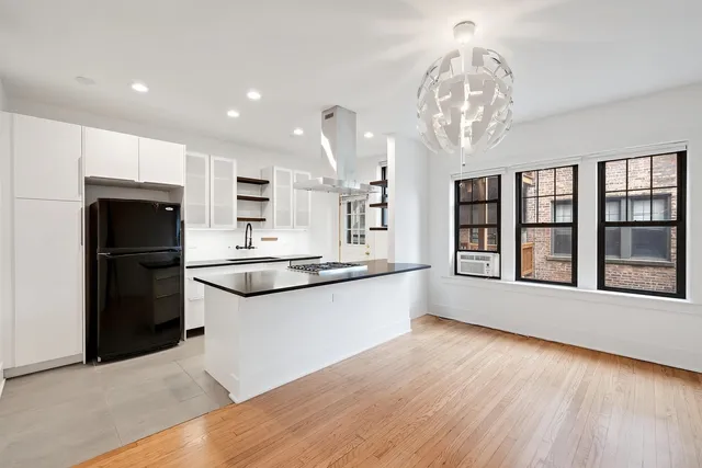 a kitchen with stainless steel appliances granite countertop a refrigerator oven a sink dishwasher and white cabinets with wooden floor