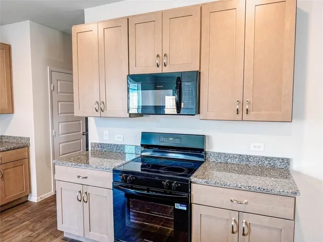 a kitchen with granite countertop a stove top oven a sink dishwasher and a refrigerator