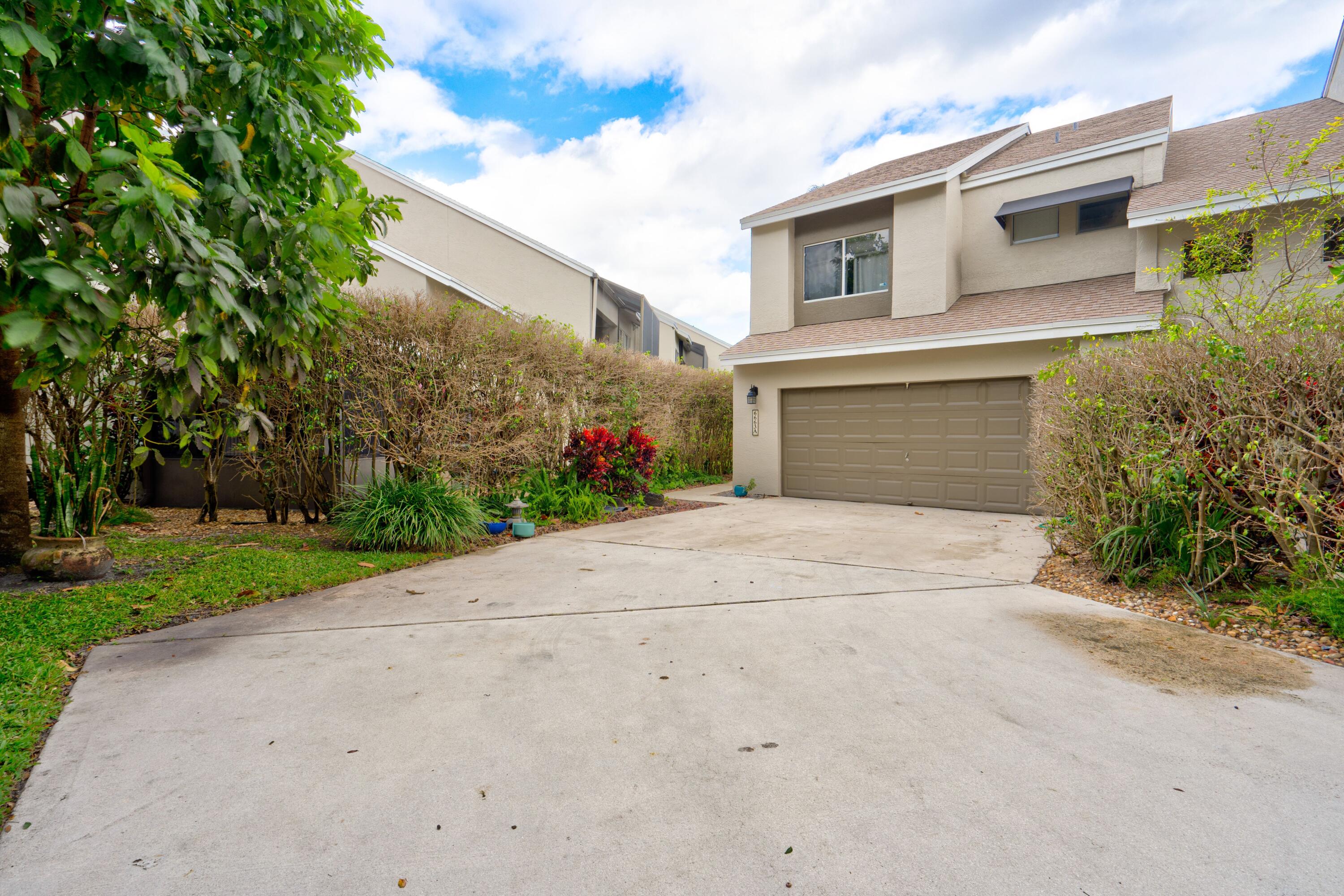 6663 Boca Pines Trail, Unit A Boca Raton, FL 33433 - Photo 12 of 60 a front view of a house with a yard and a garage