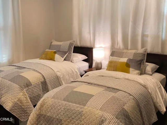 a bedroom with two beds and curtain