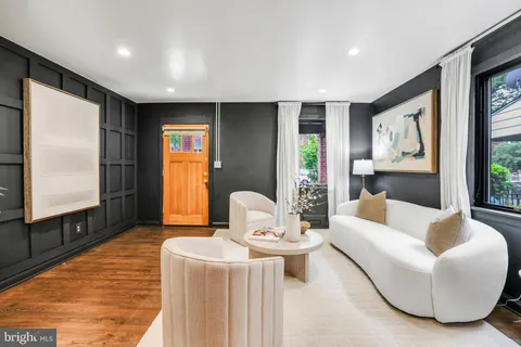 a living room with furniture a large window and wooden floor