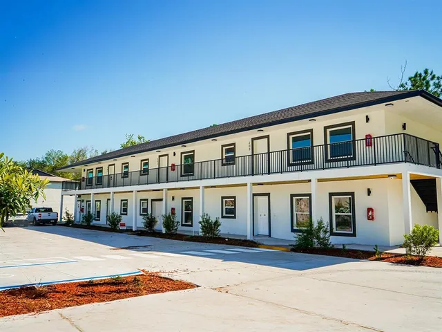 a front view of a building with a garden and plants