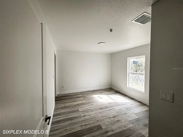 a view of an empty room with window and wooden floor