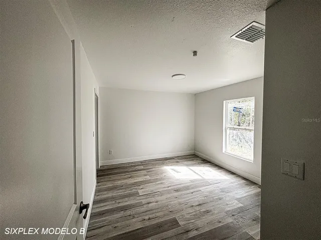 a view of an empty room with window and wooden floor