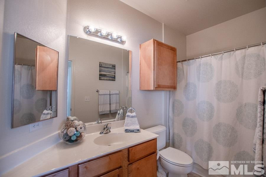 9050 Double R Boulevard, Unit NV Reno, NV 89521 - Photo 18 of 25 a bathroom with a sink a toilet and shower curtain