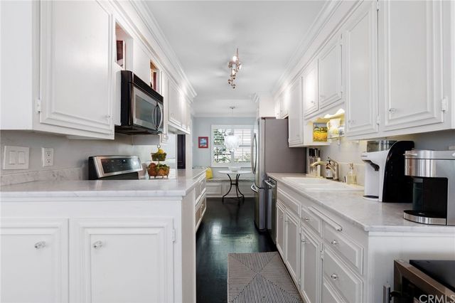 a kitchen with stainless steel appliances granite countertop a sink dishwasher stove and white cabinets