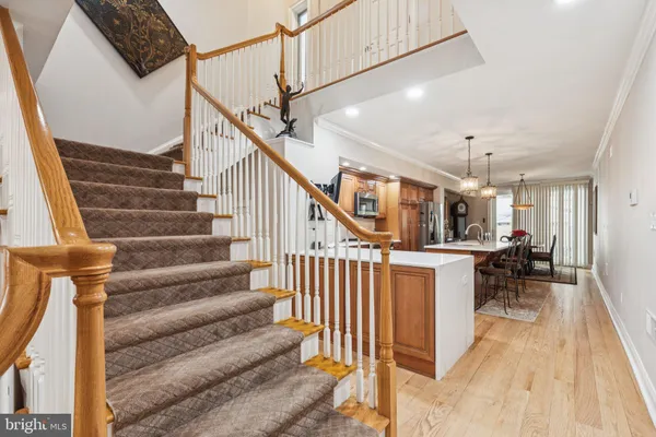 a kitchen with stainless steel appliances granite countertop a stove a sink dishwasher a refrigerator a dining table and chairs with wooden floor