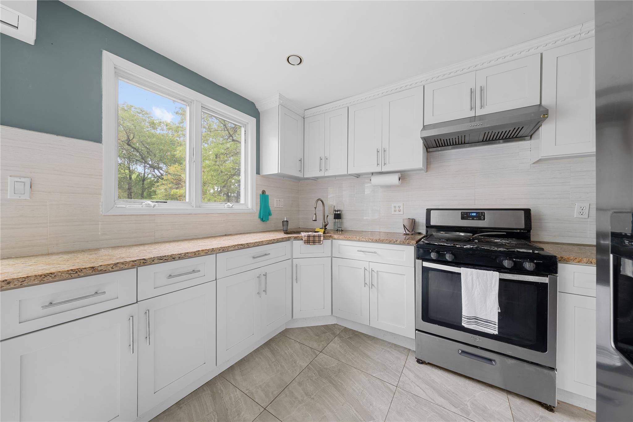 51 Joline Road Port Jefferson Station, NY 11776 - Photo 19 of 38 a kitchen with granite countertop white cabinets stainless steel appliances and a window