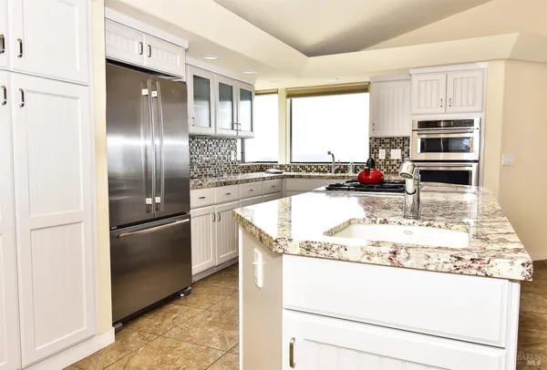 a kitchen with kitchen island granite countertop a sink stove and refrigerator