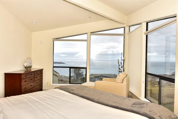 a bedroom with a bed and large windows