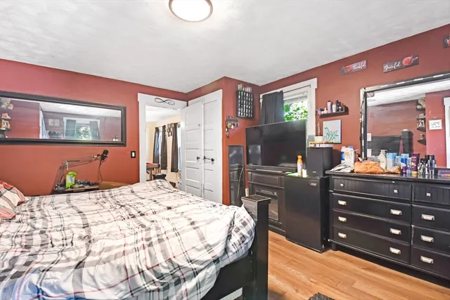 a bedroom with a bed a dresser and flat screen tv