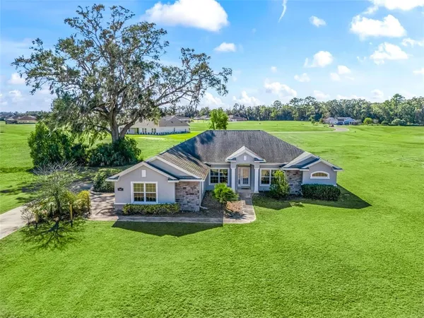 a aerial view of a house with a big yard and large trees