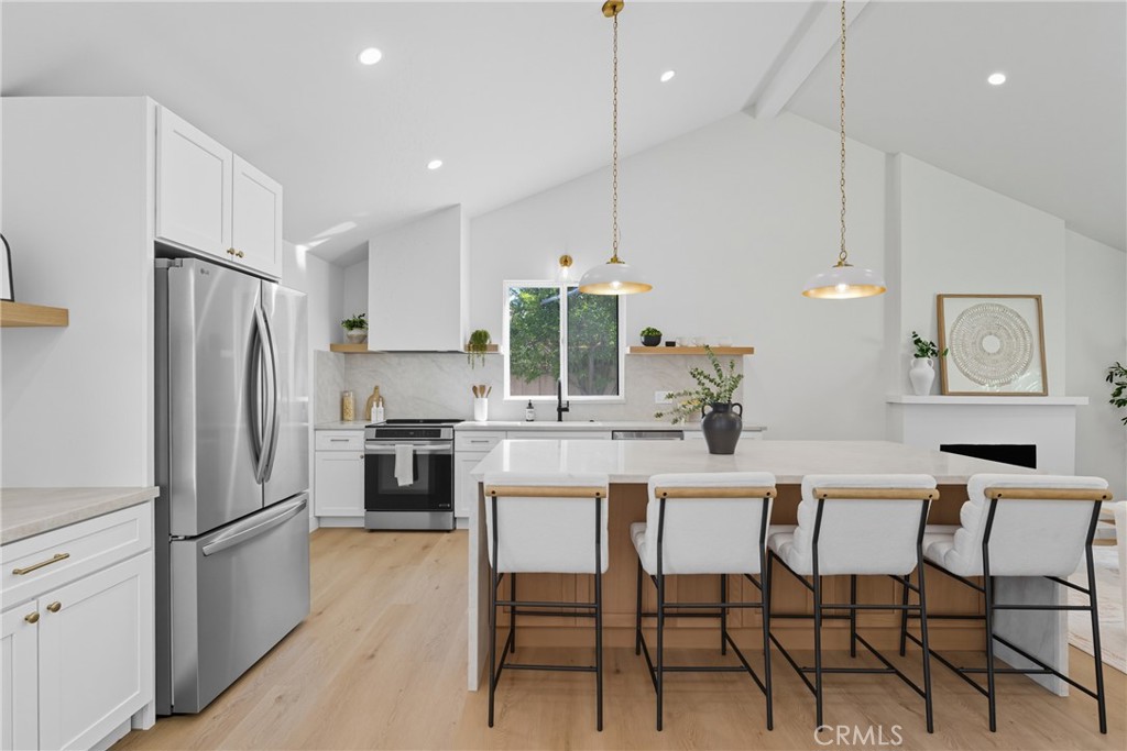 226 Tennyson Street Thousand Oaks, CA 91360 - Photo 3 of 27 a kitchen with stainless steel appliances a refrigerator a stove a dining table and chairs with wooden floor
