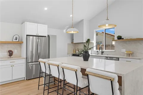 a kitchen with stainless steel appliances granite countertop a sink a stove a refrigerator and island with wooden floor