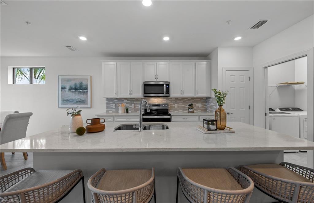 5693 Mayflower Way, Unit 1107 Ave Maria, FL 34142 - Photo 13 of 46 a kitchen with a sink a stove a microwave and cabinets