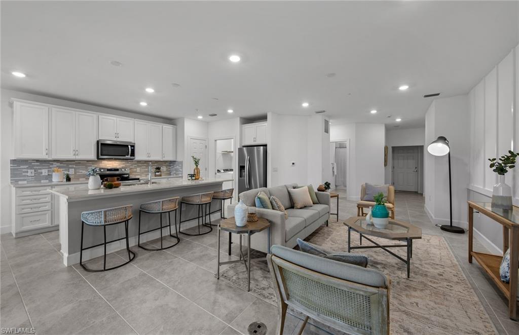 5693 Mayflower Way, Unit 1107 Ave Maria, FL 34142 - Photo 18 of 46 a living room with stainless steel appliances kitchen island granite countertop lots of white cabinets a stove a sink and a refrigerator
