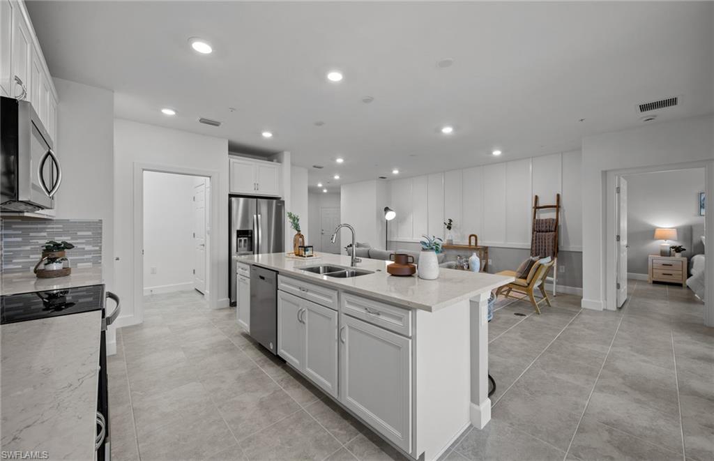 5693 Mayflower Way, Unit 1107 Ave Maria, FL 34142 - Photo 19 of 46 a large kitchen with kitchen island a sink a center island stainless steel appliances and a cabinets