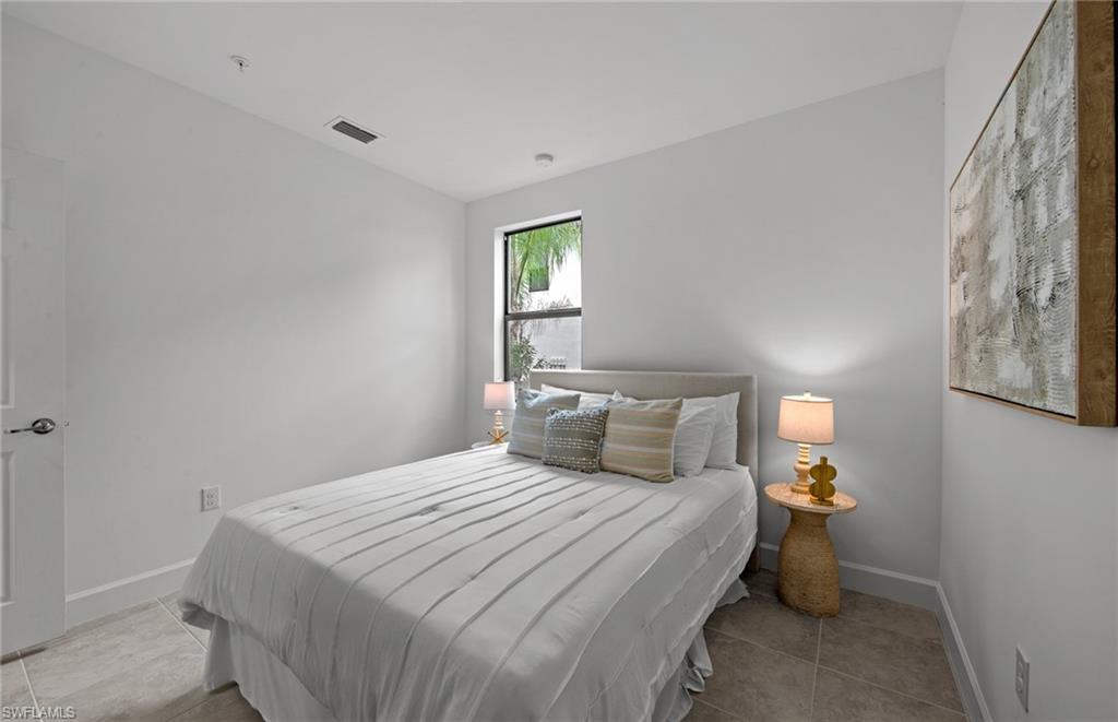 5693 Mayflower Way, Unit 1107 Ave Maria, FL 34142 - Photo 31 of 46 a bedroom with a bed and a lamp